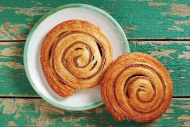 Yeşil ahşap bir tabakta tarçınlı poğaça ruloları.