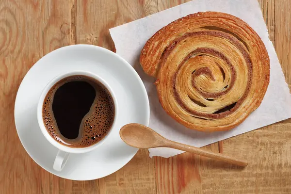 Eski ahşap arka planda bir fincan kahve ve tarçınlı börek.