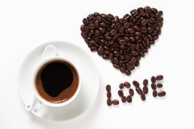 Bir fincan kahve ve kalp şeklinde kahve çekirdeği ve 