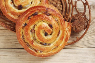 Hasır bir tabakta kuru üzümlü çörekler, ahşap bir yüzeye yakın çekim, üst manzara.