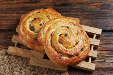 Kuru üzümlü börekler eski ahşap bir masanın üzerinde yuvarlanır.