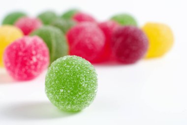 Çok renkli marmelat topları beyaz arka planda şekerle kaplıdır.