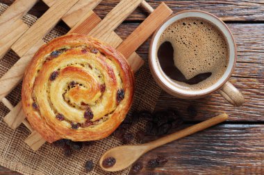 Bir fincan kahve ve poğaça üzümlü çörek kırsal ahşap masa, üst manzara