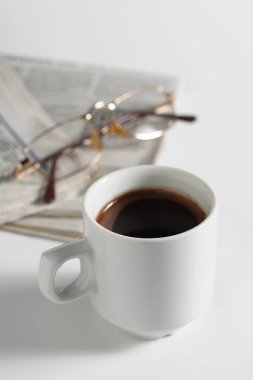 Beyaz arka planda bir fincan kahve, gazete ve bardak.