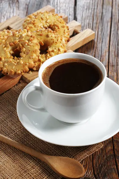 Cup of coffee and cookies rings with nuts on old wooden background