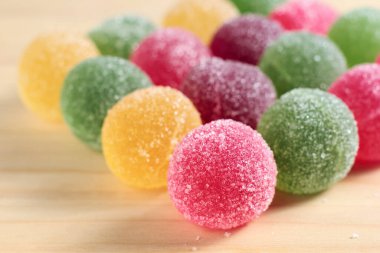 Çok renkli marmelat topları ahşap arka planda şekerle kaplanmış.