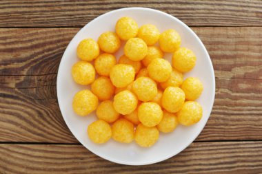 Tahta arka plandaki tabakta peynir aromalı mısır topları.