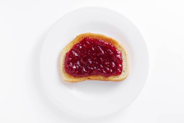 Beyaz arka planda bir tabakta ahududu reçelli kızarmış beyaz ekmek.