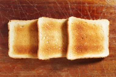 Eski ahşap bir masanın üstünde kızarmış ekmek dilimleri.