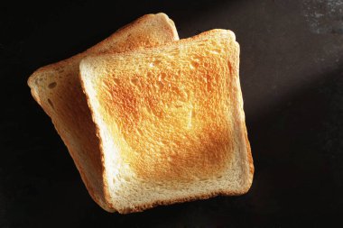 Arka planda siyah tepside kızarmış ekmek, üst manzara. Sert yönlü ışık