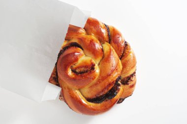 Eski ahşap bir masada, kağıt torbada çikolatalı çörek.