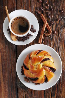 Çikolatalı çörek ve eski ahşap arka planda bir fincan kahve.