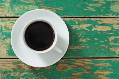 Eski yeşil ahşap arka planda bir fincan kahve, fotokopi alanı olan üst manzara.