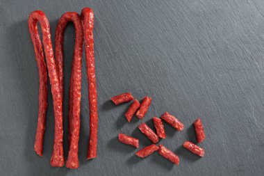 İnce Kabanos Sosisi ve siyah taş arka planda dilimler, kopya alanı ile üst görünüm