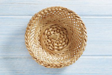 Mavi ahşap zemin üzerinde boş hasır kase, üst görünüm