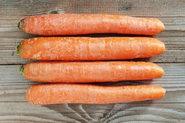 Eski ahşap arka planda taze havuç. Masada portakal kökleri var. Üst görünüm