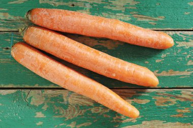 Eski yeşil ahşap arka planda taze turuncu havuçlar, üst manzara.