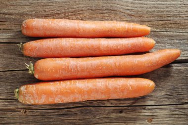 Eski ahşap arka planda taze havuç. Masada portakal kökleri var. Üst görünüm