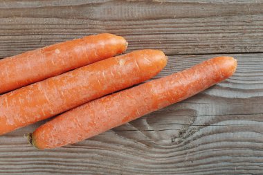 Eski ahşap arka planda taze havuç. Masada portakal kökleri var. Üst görünüm