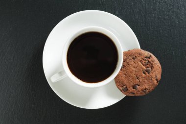 Siyah taşlı arka planda çikolatalı kurabiyeler olan bir fincan kahve.