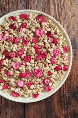 Tahta arka planda tabakta kızartılmış yaban mersinli müsli.