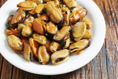 Sarımsakla pişirilmiş midye. Ahşap arka planda bir tabak. Yakın plan.