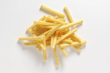 Beyaz arka planda bir yığın tuzlanmış patates çubuğu.