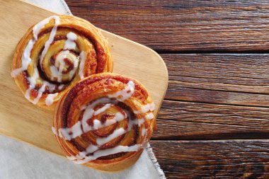 Tarçın tomarı, tahta arka planda kesme tahtasında krema ile kaydırır, kopyalama alanı ile üst görünüm