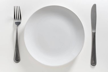 Beyaz arka planda boş tabak ve çatal bıçak takımı, üst görünüm