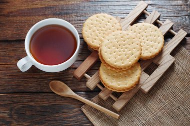 Yuvarlak sandviç kurabiyeleri ve bir fincan çay eski ahşap masa, üst manzara