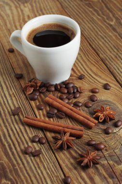 Ahşap arka planda bir fincan kahve ve baharat.