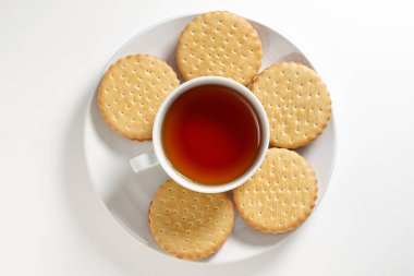 Beyaz arka planda bir tabakta çay ve yuvarlak sandviç kurabiyeleri.