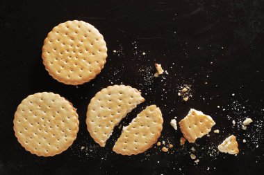 Yuvarlak kurabiyeler bütün ve siyah tepside kırılmış, üst manzara