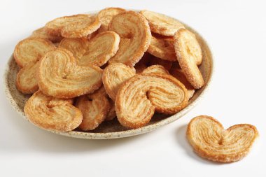 Palmiyeler beyaz arka planda bir tabakta hamur işi kurabiyeleri tüttürür