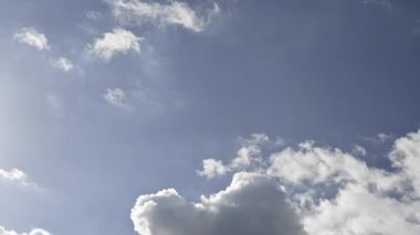 White and gray autumn clouds cross the sky from top left to bottom right. Blue sky, sunny afternoon with cumulus clouds passing quickly. Low-angle timelapse looping seamless.