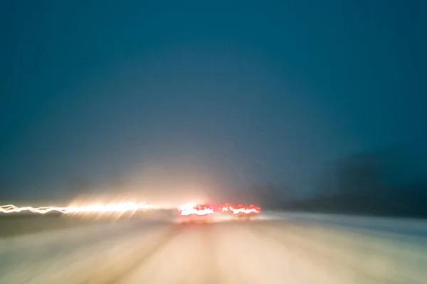 夜間高速道路で雪が降る悪天候で運転し 長い露出撮影によって作成された軽いトレイルでモーションブラー ストックフォト