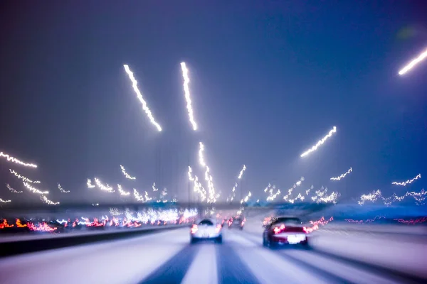 在恶劣的天气条件下驾驶 城市高速公路上下着雪 长时间曝光摄影所产生的光迹模糊了运动 图库图片
