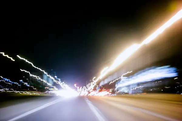 开车在夜晚的城市街道上 抽象的运动模糊了 由长曝光摄影所产生的光迹 图库图片