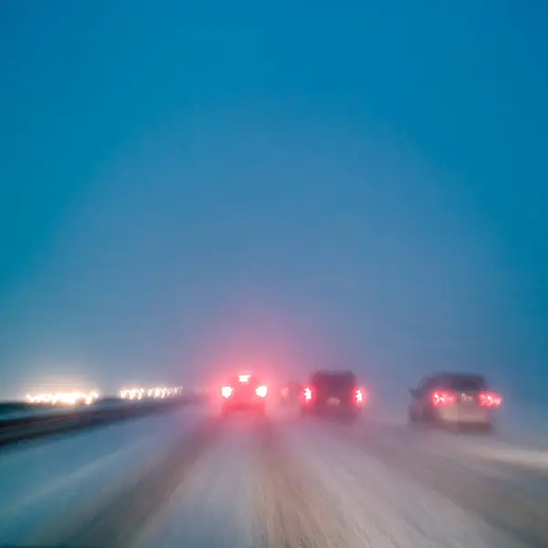 在恶劣的天气条件下开车 夜间高速公路上下着雪 长时间暴露在摄像机中 模糊了方向 图库图片