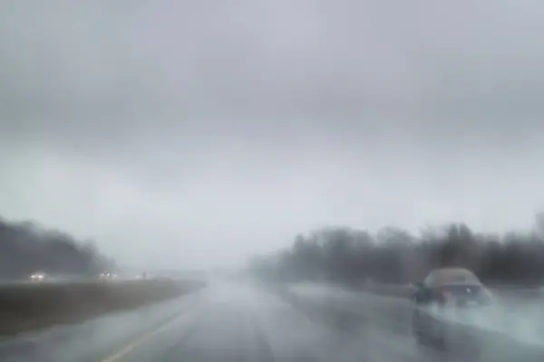 汽车在恶劣的天气条件下驾驶 高速公路上大雾和大雨 长时间暴露在相机中 模糊了方向 图库照片