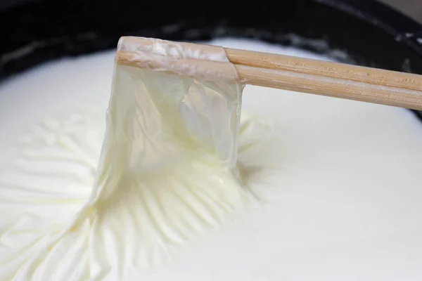牛乳の表面から乳の皮を木の棒で取り除き — ストック写真