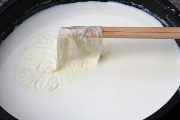 用木棍从牛奶表面除去牛奶皮 — 图库照片