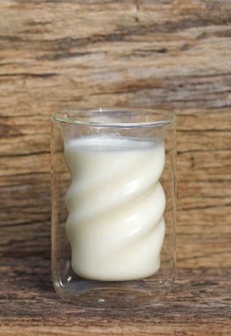 Ahşap arka planda bir bardak taze süt.