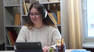 Genç, güzel bir kız, uzun kahverengi saçlı, gözlüklü, sıcak, samimi bir atmosferde müzik dinleyen duygusal ve jestler yapan bir öğrenci. Yavaş çekim.