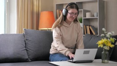 Genç ve güzel bir kız öğrenci, kulaklık takıyor, bilgisayarda çalışıyor, öğrenci arkadaşlarıyla iletişim kuruyor, olumlu duygular ifade ediyor. Ev ortamı. Yavaş çekim..
