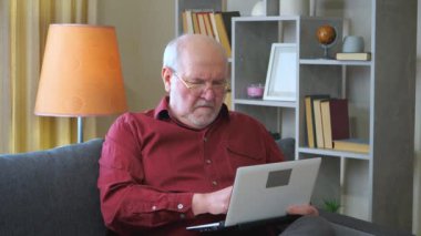 Yaşlı bir işadamı, gri saçlı, bordo bir gömlek giyiyor, evde, muhasebe raporu üzerinde çalışıyor. O çok odaklanmış. Yavaş çekim.