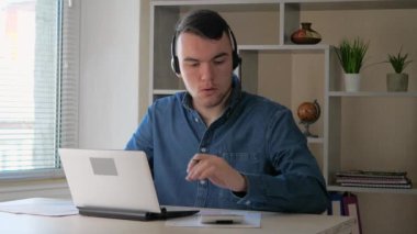  Mavi gömlekli genç, yakışıklı bir işadamı, bir muhasebe raporu üzerinde çalışıyor, bir hesap makinesi kullanarak verileri uzlaştırıyor ve bilgisayara giriyor. Yavaş çekim.