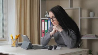 Gri bluzlu, koyu renk dalgalı saçlı güzel bir kız bilgisayarın yanına oturur ve uyur. Yavaş Hareket