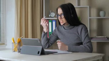  Gözlüklü ve kulaklıklı genç bir kız, bir öğrenci, bilgisayar kullanarak arkadaşlarıyla iletişim kuruyor, duygusal olarak haklı olduğunu kanıtlıyor, jestler yapıyor ve sinirleniyor. Yavaş Hareket
