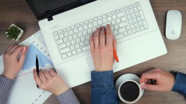 Kadın ve erkek yöneticilerin elleri masanın üstünde, iş yapmak için eşyalarla birlikte. Hesap makinesi ve bilgisayar kullanan yöneticiler yıllık mali rapordaki verileri hesaplarlar.